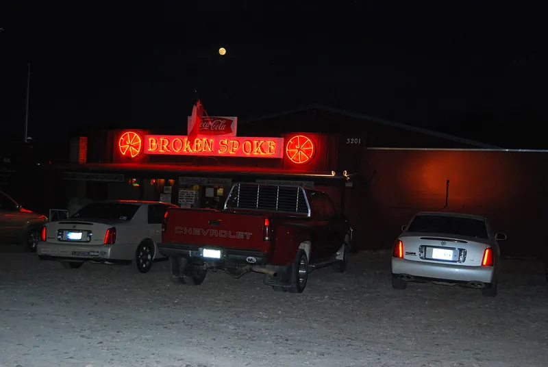 The Broken Spoke dance hall in Austin at night, with its lit sign by the road.