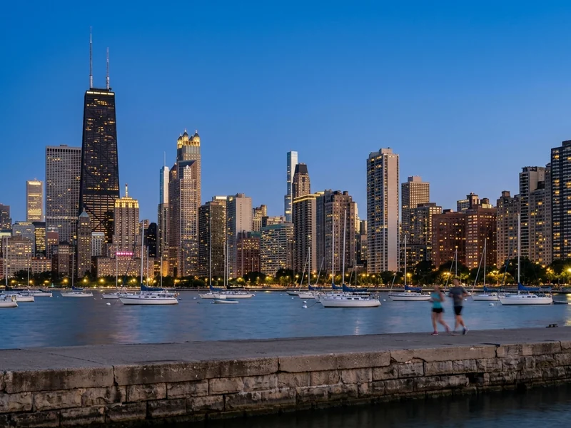The Chicago skyline above the sailboats of a Lake Michigan harbor at dusk.