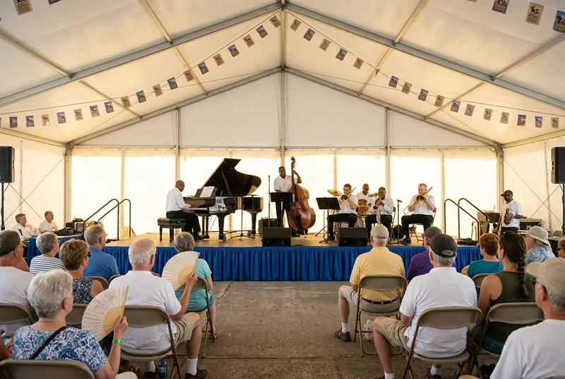 A jazz band playing to a seated crowd in a tent at New Orleans Jazz Fest.