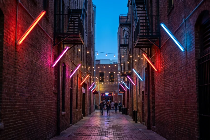 Printers Alley in downtown Nashville at blue hour, a brick lane lit by neon signs.