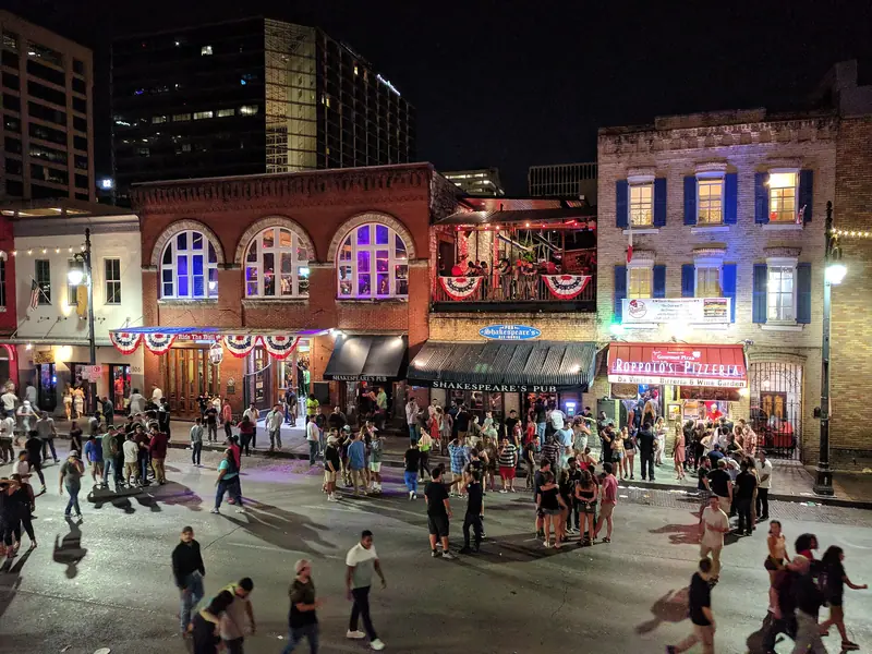 Sixth Street in Austin at night, with bar and club signs along both sidewalks.
